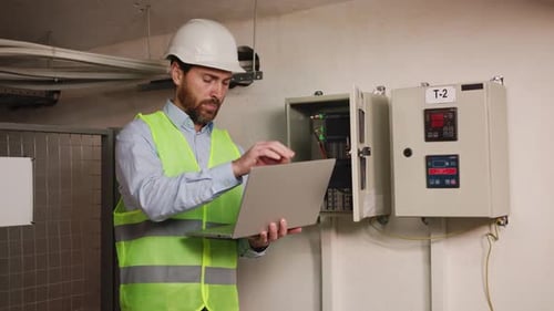 Engineer Inspecting Equipment with Laptop in Industrial Setting