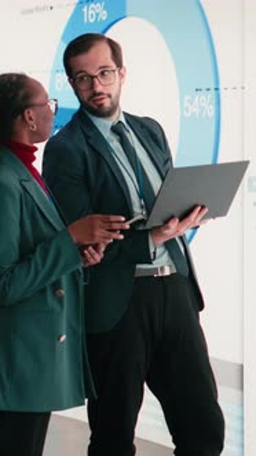 Vertical Video Corporate Managers Evaluate Fiscal Performance Metrics on Digital Wall