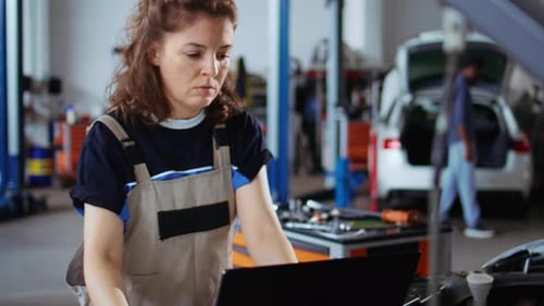 Female Mechanic Using Laptop Inspecting Car in Auto Shop