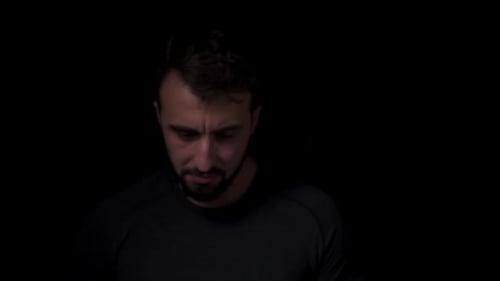 Man with Beard Looking Towards Camera in Darkness