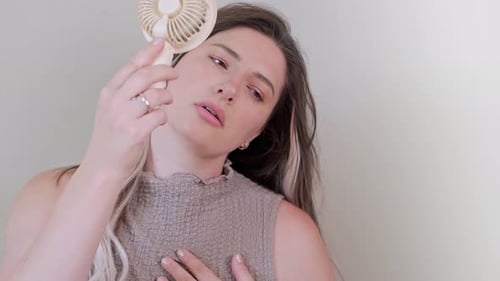 Woman Cooling Down with Portable Fan Indoors