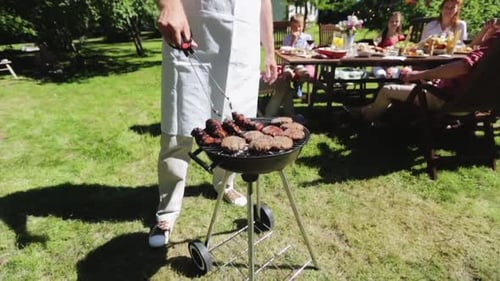 Man Cooking Meat on Barbecue Grill at Summer Garden Party Adult