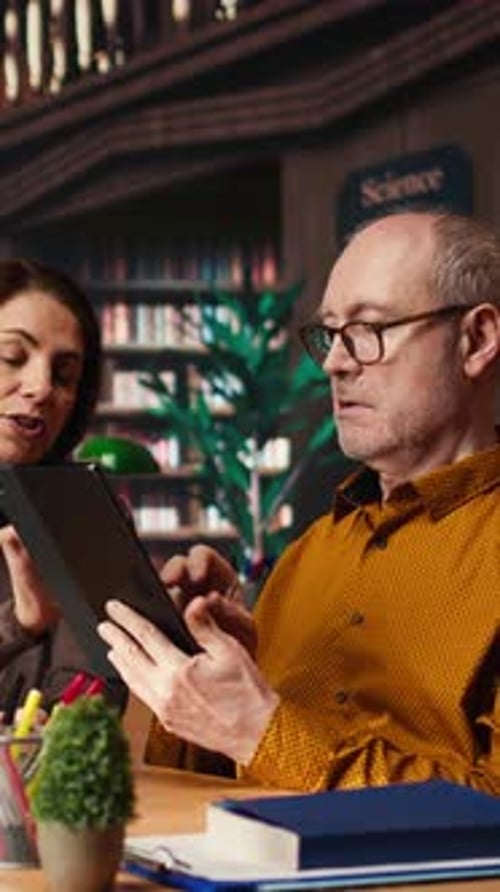 Vidéo verticale Étudiants adultes complétant leurs notes de cours sur des papiers et une tablette