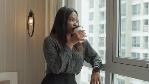 Stylish Woman Drinks Coffee at Apartment Window
