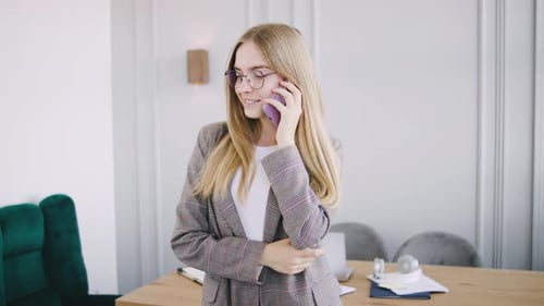 Young Professional Woman Engaged in a Phone Call While Standing in a Modern Office Environment