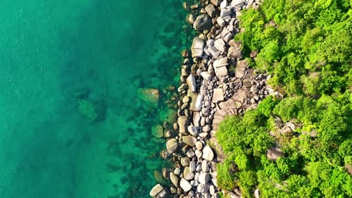 Flying over sea waters along the rocky coastline in tropical island.