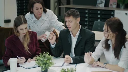 Employees Work Together While Sitting at a Table in a Modern Office Young Man in a Business Suit