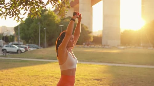 Woman Exercising with Resistance Band in Park at Sunset