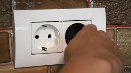 European double power socket. Plugging and unplugging the device by a a woman.