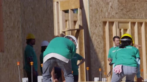 Volunteers building construction site carry wooden beam