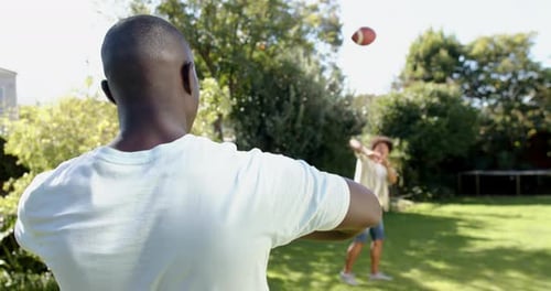 Men Throwing Football in Suburban Backyard on Sunny Day