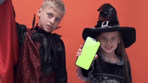 Kids in Halloween Costumes Holding Smartphone
