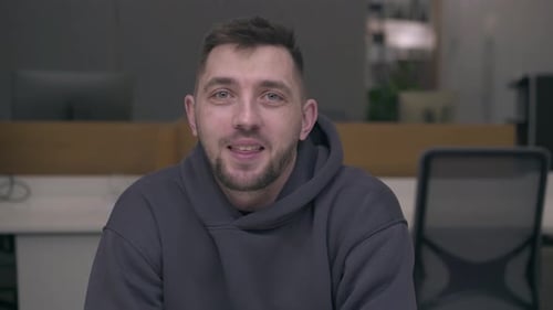 Smiling Man Wearing Hoodie in Workplace Setting