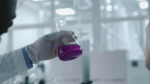 Verschiedene Kollegen untersuchen eine Probe einer lila Flüssigkeit in einer Flasche im Labor