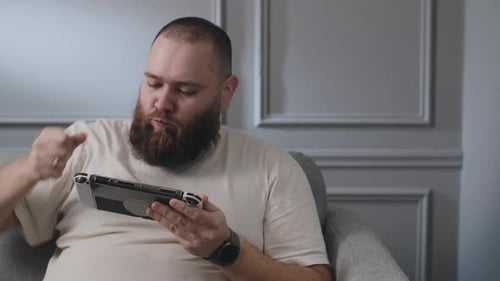 Man Plays Handheld Console at Home