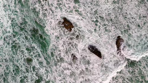 Pull in, aerial, birds eye view, drone shot of large, strong waves, powerfully crashing on a set of