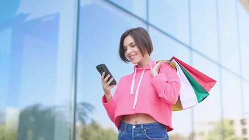 Stylish Woman Using Phone After Shopping