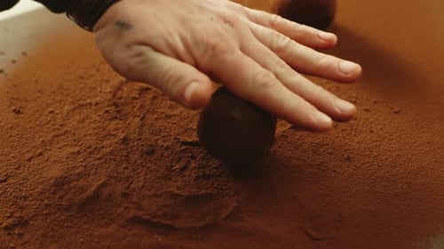 Closeup Man Hand Rolling Chocolate Truffle in Cocoa Powder In