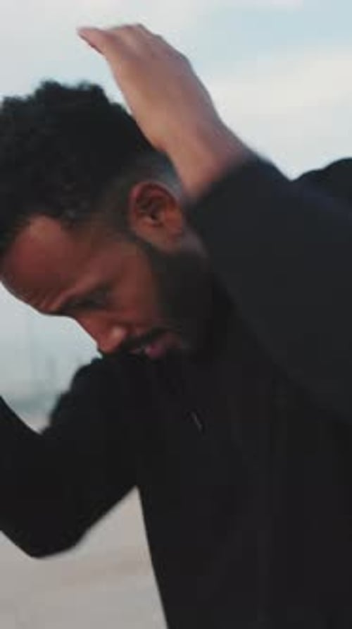 Young athlete doing warm-up before training while standing on the embankment