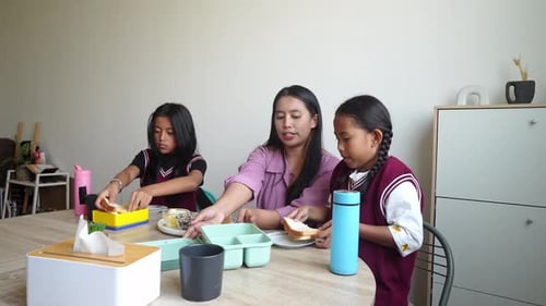 Asian Mother Teaching Her Daughters To Preparing Lunchbox Before Go To School