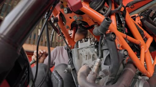 Mechanic Repairing a Motorcycle Engine in Garage