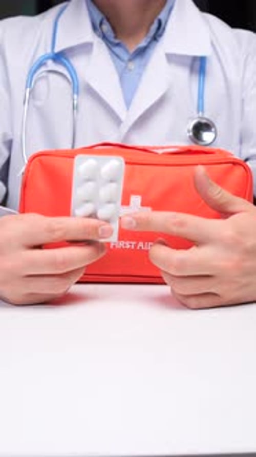 Doctor holding blister pack of pills near first aid