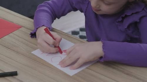 Girl Drawing on Paper with Crayon at Table