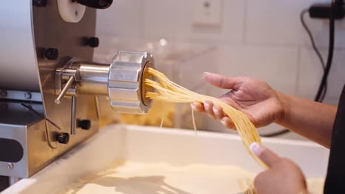 Köchin macht hausgemachte Spaghetti mit einer Maschine, eng