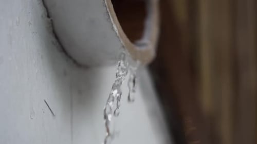 Fresh rain water dripping out of raised white drain pipe gutter in Indonesia, Asia during heavy stor