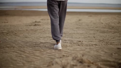 Closeup of a Person Walking on a Sandy Beach Focusing on Their Sneakers