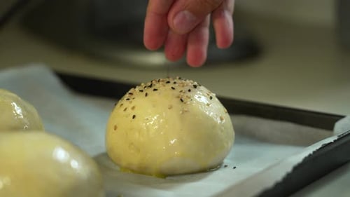 Hands Sprinkle Sesame Seeds on Dough Ball