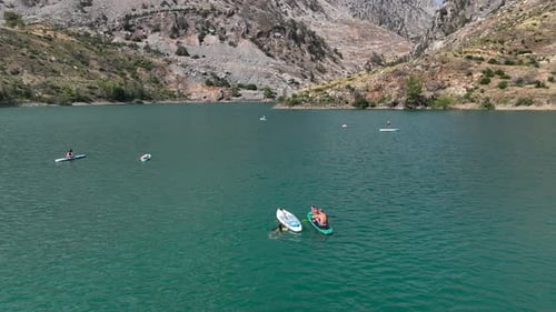 A Peaceful Paddleboarding Journey Through the Canyon with People Swimming and Relaxing in the Sun