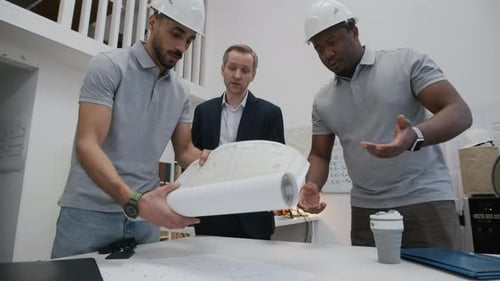 Multiethnic Engineers Discussing Renovation Project with Blueprint in Office