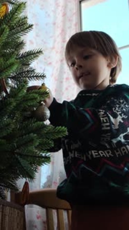 Child Decorating Christmas Tree with Gold Ornaments