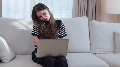 Woman Working on Laptop While Talking on Phone