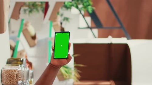 Vertical Video Storekeeper Holds Mobile Phone with Greenscreen Display