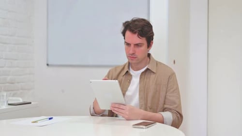 Man Working at Desk Using Digital Tablet