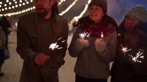Cheerful Friends Have Fun Partying with Sparklers in Hands at Christmas Market People Jump and Dance
