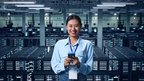 An Asian Business Woman Using Mobile Phone And Smiling To Camera In Data Center