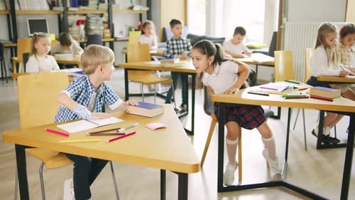 Two Classmates a Boy and a Girl Elementary School Students are Sitting at Neighboring Desks and