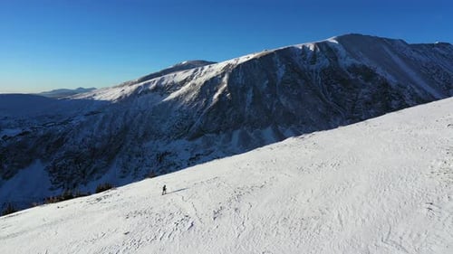 Luftbild, Bergsteiger beim Wandern mit Schneeschuhen auf einem schneebedeckten Hügel in wunderschöner Winterlandschaft von