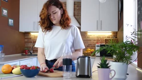 Woman cutting strawberries to make a healthy smoothie