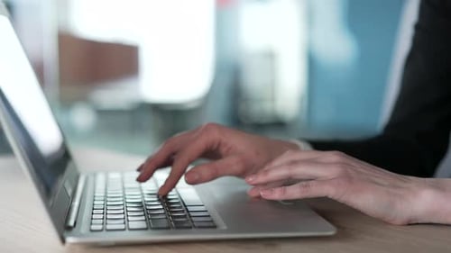 Close up of female hands typing on laptop keyboard in modern office