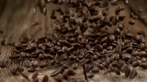 Roasted Coffee Beans Falling on Rustic Wooden Surface