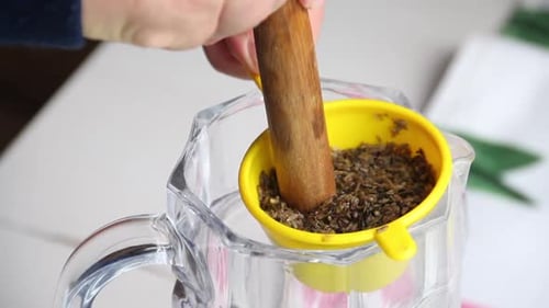Um homem espreme vodka com infusão de flores de lavanda. Passa por uma peneira. Tintura de lavanda em
