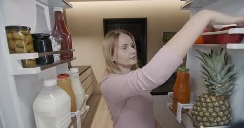 Woman Choosing Food From Refrigerator in Modern Home