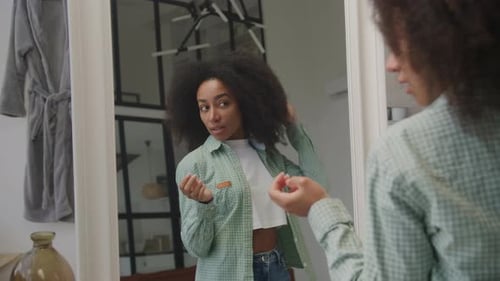 Schwarze Frau bewundert sich selbst im Spiegel Junge erwachsene afroamerikanische Frau checkt sich selbst aus und