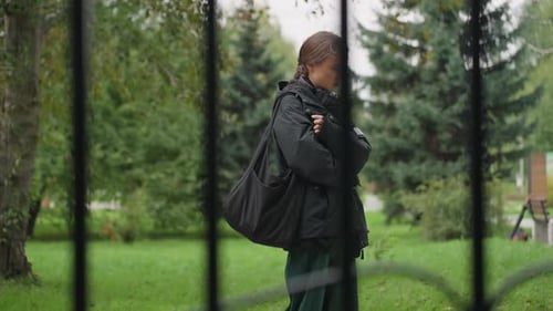 Woman with Headphones Looks Downcast in Park