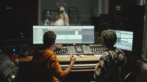 Music Producers Mixing Sound as Singer Recording Vocals in Audio Studio