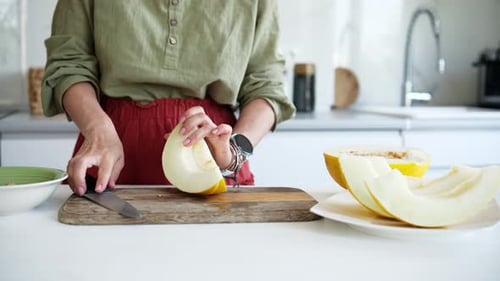 Frau schneidet Melone in Stücke